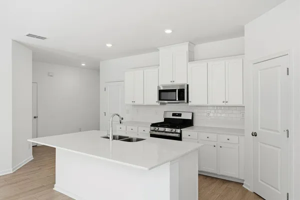 a kitchen with stainless steel appliances a stove a sink a refrigerator and cabinets