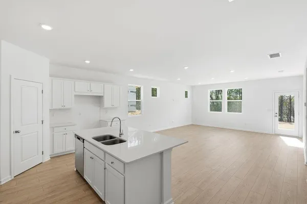 a kitchen with a sink stove and wooden floor