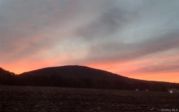a view of mountain with sunset in background