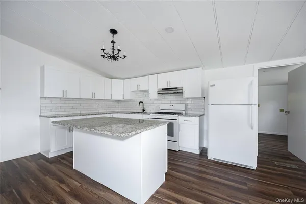 a kitchen with stainless steel appliances granite countertop a sink stove a refrigerator and white cabinets with wooden floor