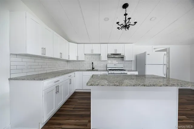 a kitchen with kitchen island granite countertop a sink cabinets and stainless steel appliances