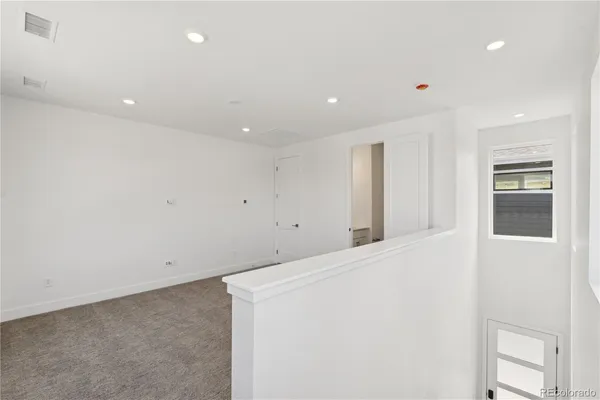 a view of an empty room with wooden floor and kitchen