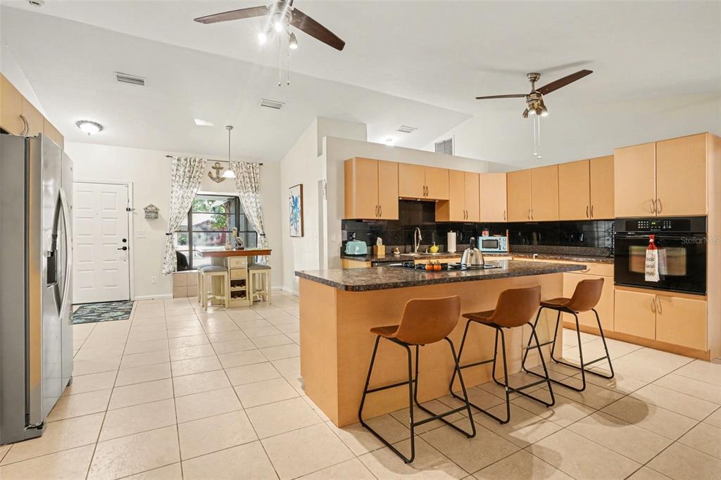 4105 Spring Way Circle Valrico, FL 33596 - Photo 10 of 34 a kitchen with stainless steel appliances kitchen island granite countertop a refrigerator a stove a sink with a dining table and chairs