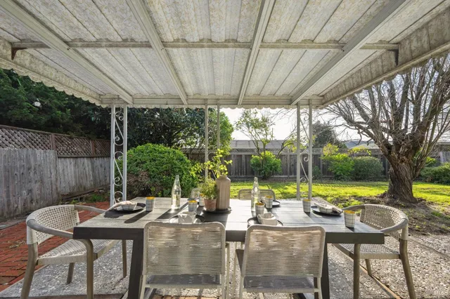 a view of a patio with table and chairs potted plants with wooden floor and fence