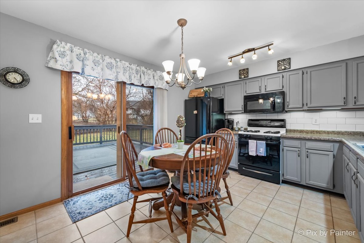 705 Cherry Tree Lane Genoa, IL 60135 - Photo 5 of 31 a kitchen with stainless steel appliances granite countertop a stove top oven a sink dishwasher a dining table and chairs with wooden floor