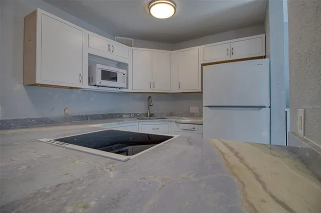 a kitchen with granite countertop white cabinets white stainless steel appliances and sink