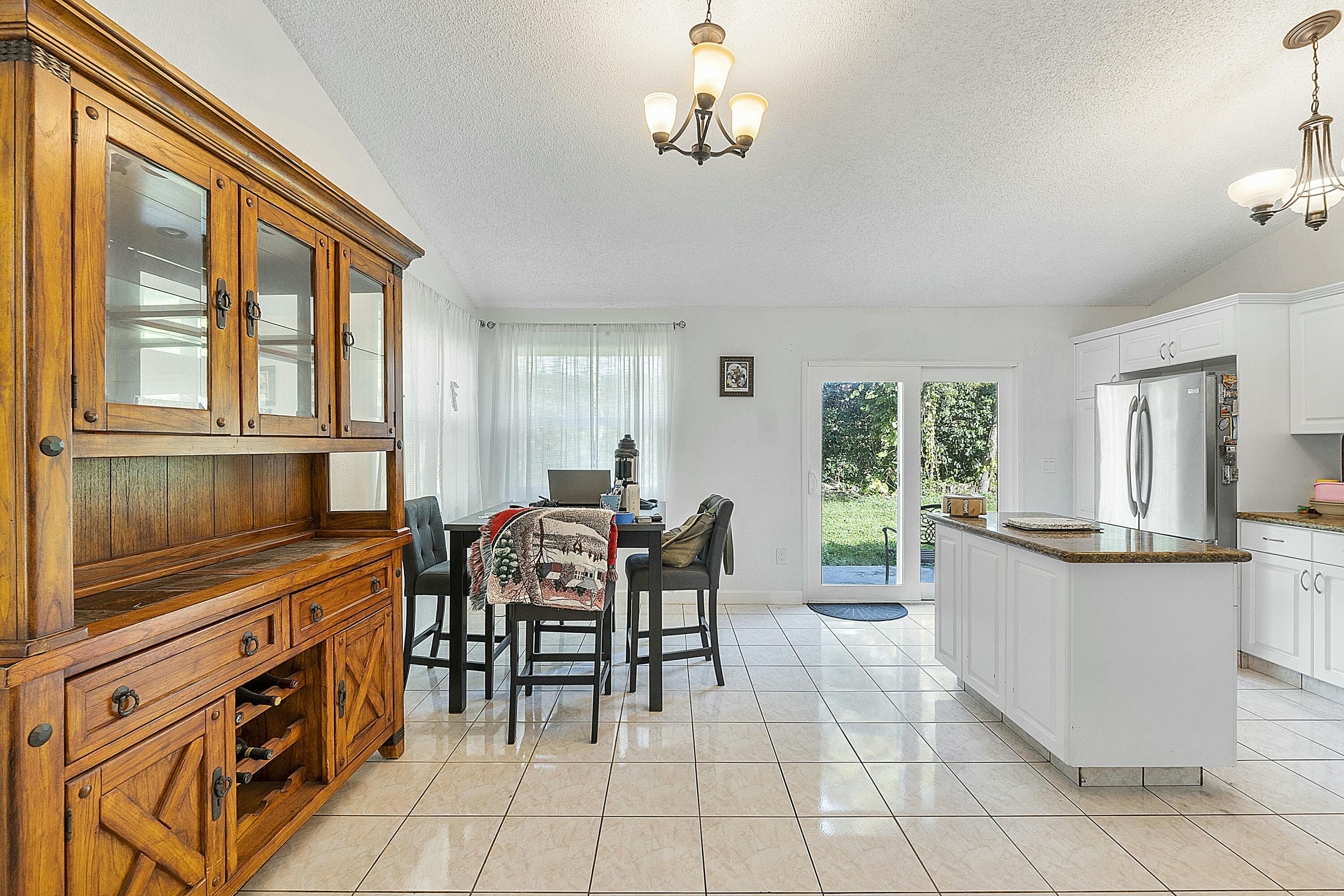 8143 Cedar Hollow Lane Boca Raton, FL 33433 - Photo 12 of 29 a kitchen with stainless steel appliances granite countertop a stove top oven a dining table and chairs with wooden floor