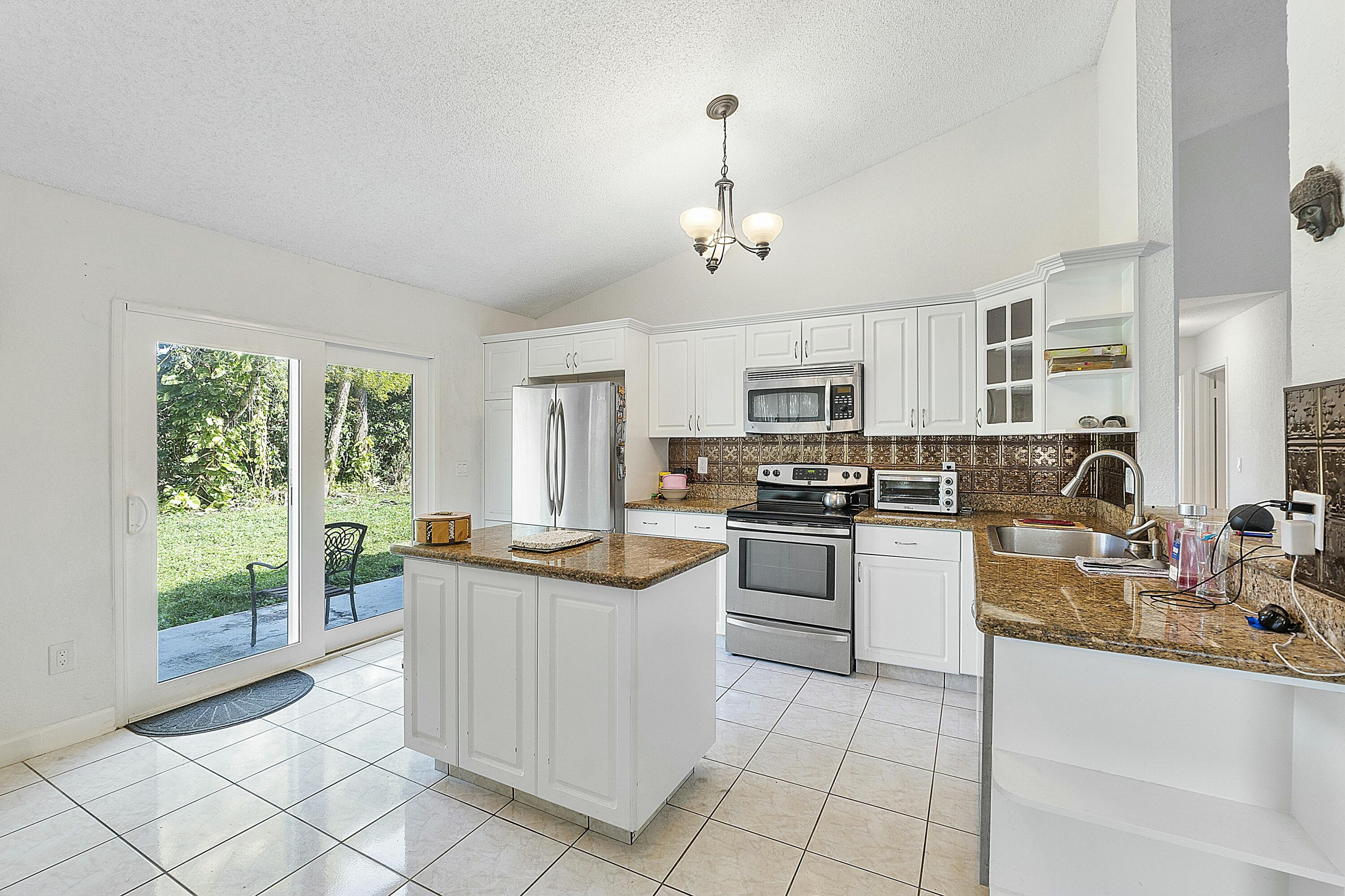 8143 Cedar Hollow Lane Boca Raton, FL 33433 - Photo 13 of 29 a kitchen with white cabinets and appliances