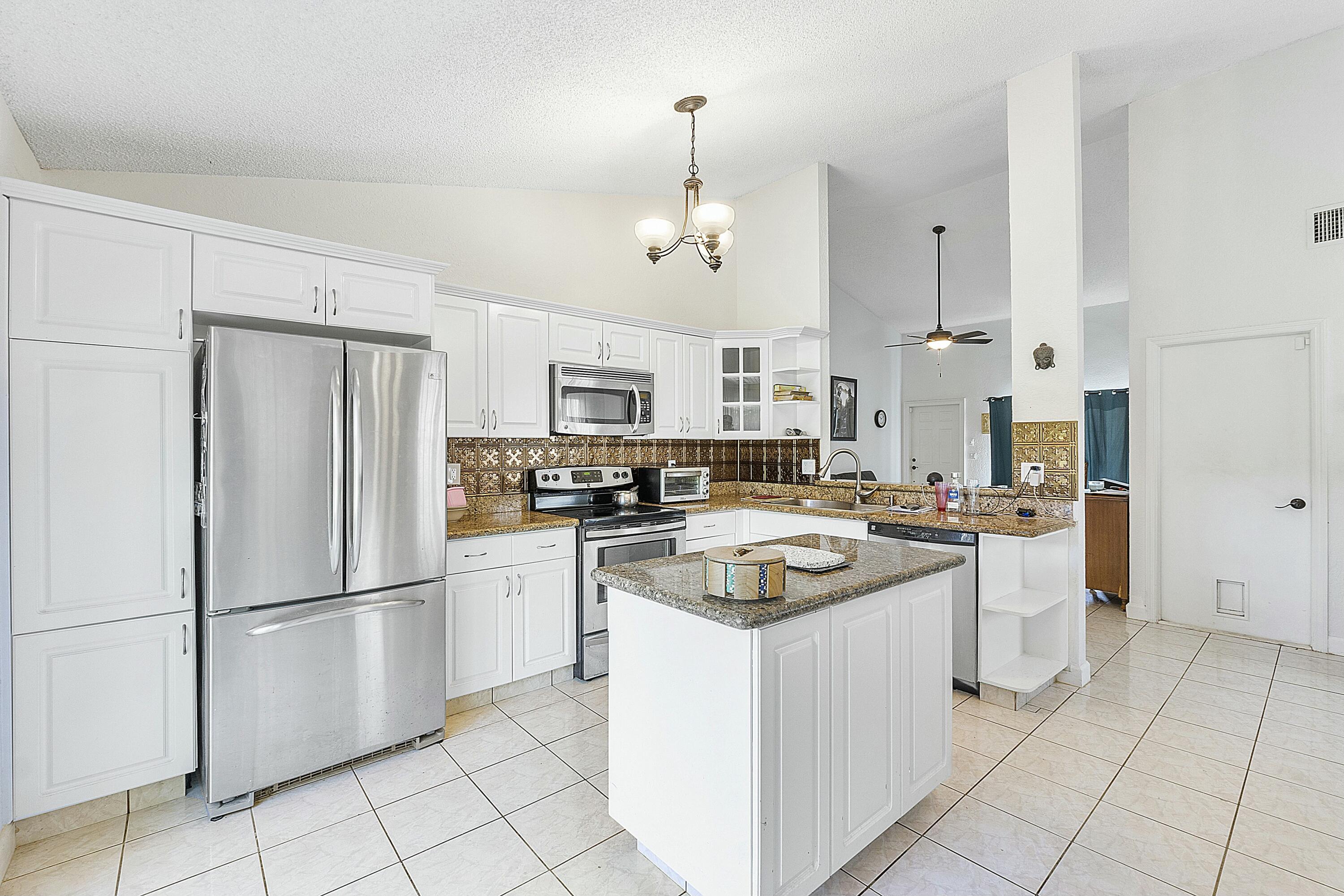8143 Cedar Hollow Lane Boca Raton, FL 33433 - Photo 14 of 29 a kitchen with white cabinets and white appliances