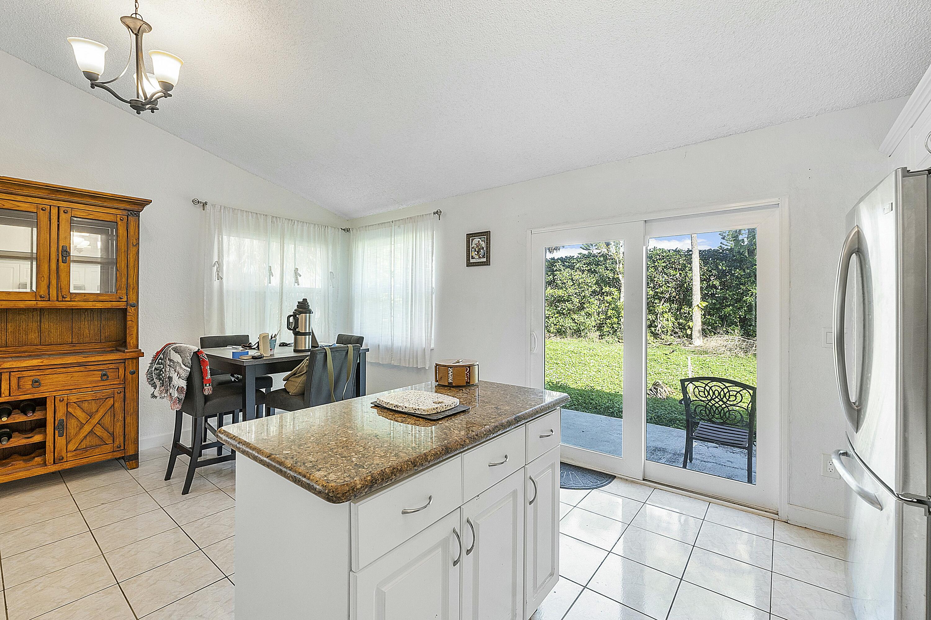 8143 Cedar Hollow Lane Boca Raton, FL 33433 - Photo 16 of 29 a kitchen with a refrigerator a sink and dishwasher with a dining table