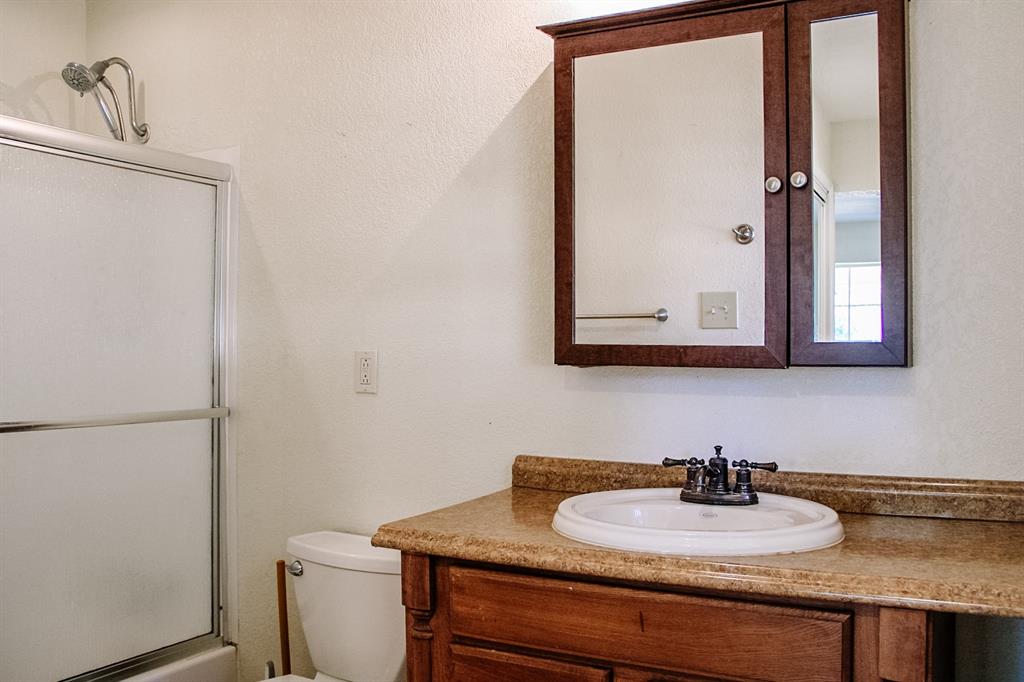 311 Spann Street Bangs, TX 76823 - Photo 12 of 17 a bathroom with a granite countertop sink and a mirror