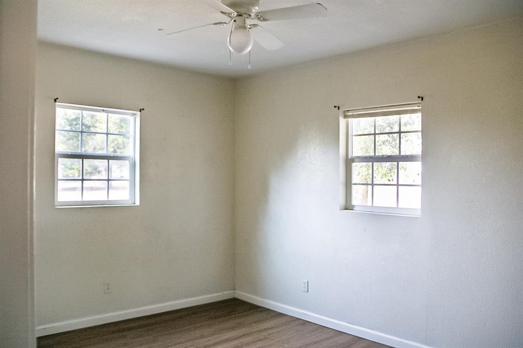 311 Spann Street Bangs, TX 76823 - Photo 15 of 17 an empty room with wooden floor windows and fan