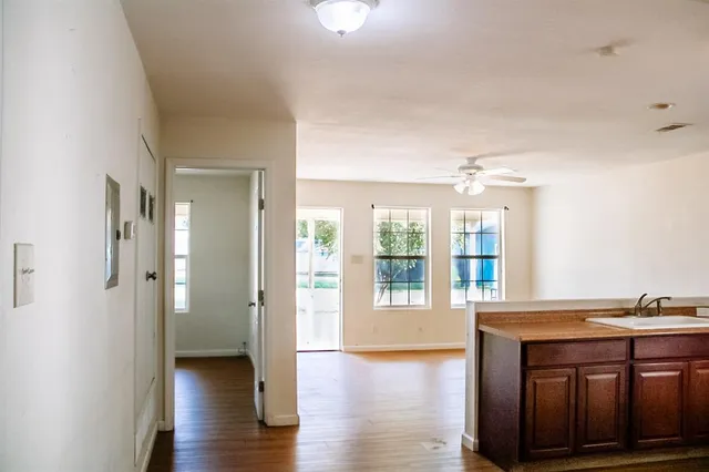 a view of a hallway with wooden floor and a kitchen