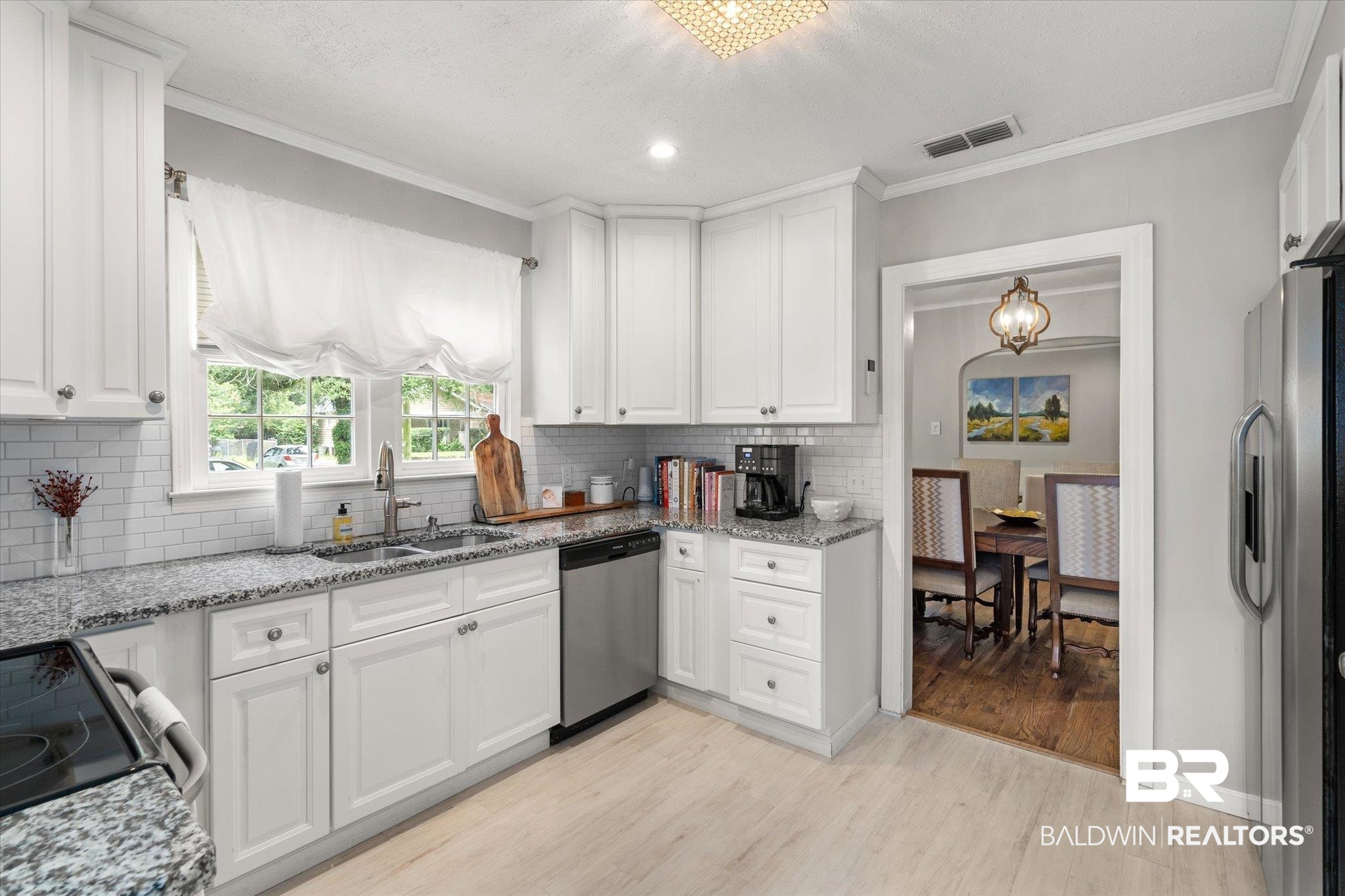 165 Crenshaw Street Mobile, AL 36606 - Photo 7 of 21 Kitchen featuring stainless steel appliances, light wood-style flooring, ornamental molding, white cabinetry, and tasteful backsplash