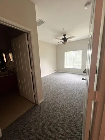 an empty room with windows and a ceiling fan