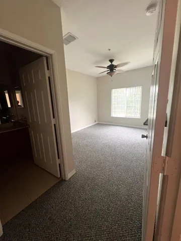 an empty room with windows and a ceiling fan