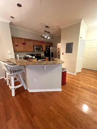 a view of a kitchen with kitchen island stainless steel appliances wooden floor and living room view