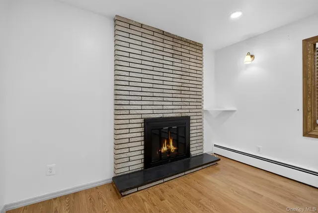 a view of an empty room with wooden floor and a fireplace