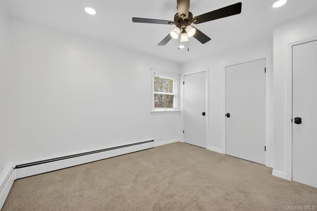 an empty room with a chandelier fan and windows