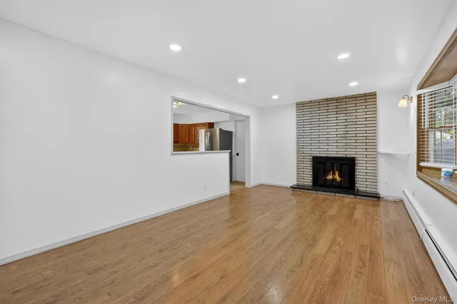 a view of empty room with wooden floor and fireplace