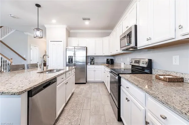 a open kitchen with stainless steel appliances granite countertop a sink dishwasher and white cabinets with wooden floor