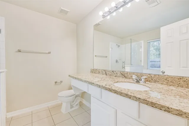 a bathroom with a granite countertop sink a toilet and a mirror