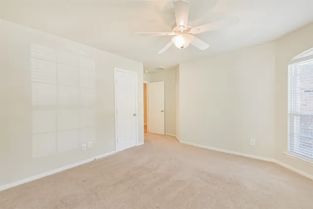 an empty room with windows and fan