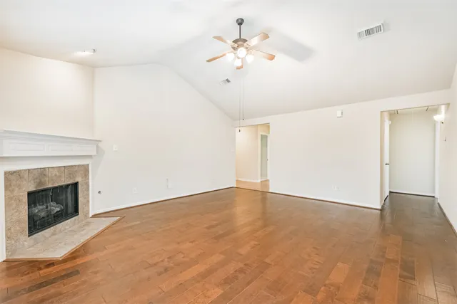 an empty room with fan and fireplace