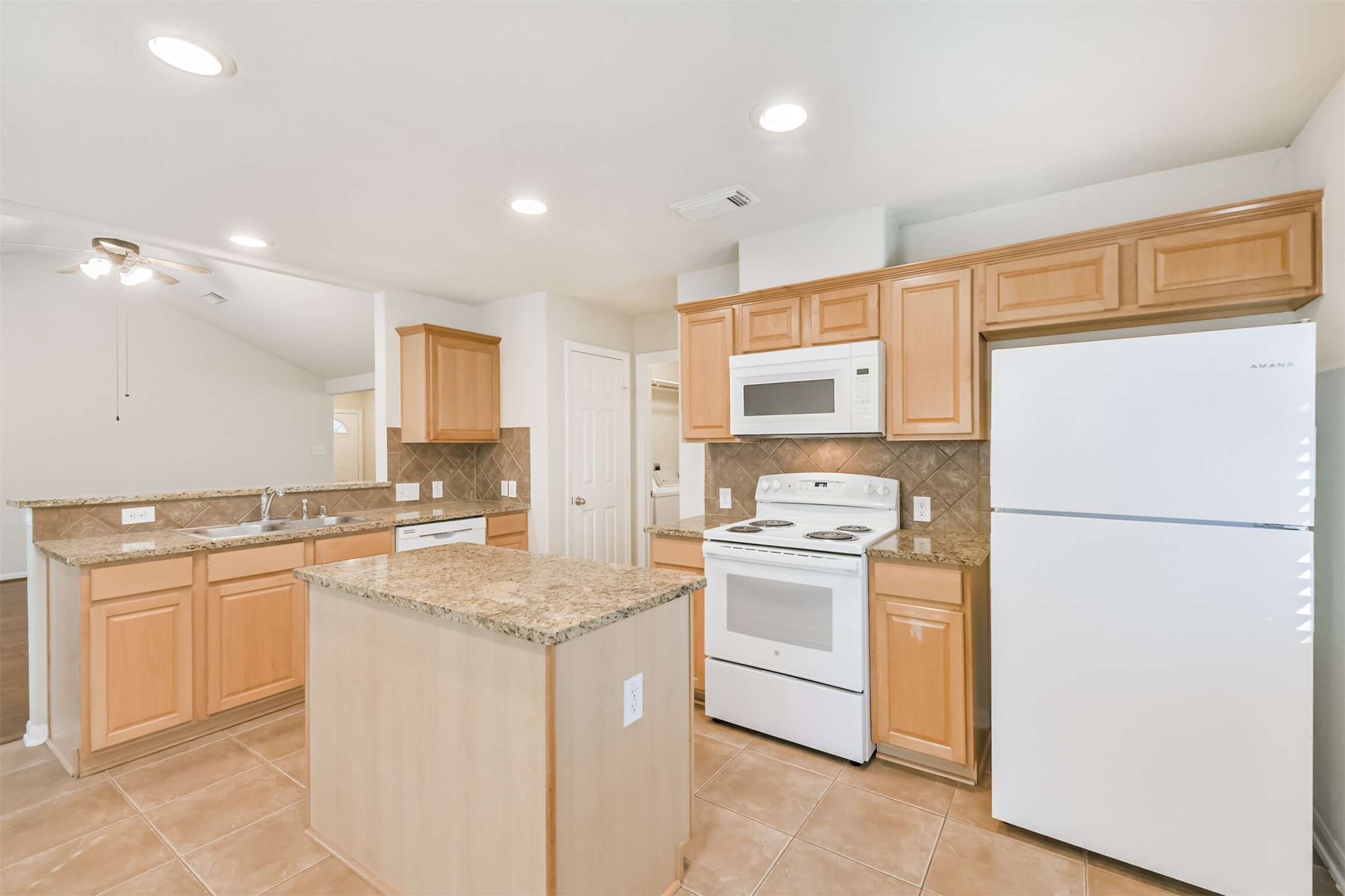 42 Prairie Oak Drive Conroe, TX 77385 - Photo 10 of 33 a kitchen with kitchen island a sink a stove a refrigerator and white cabinets