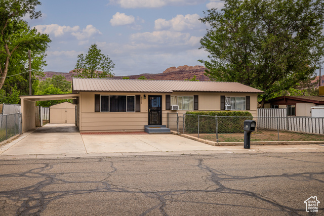 Single story home with driveway, metal roof, an attached carport, a mountain view, and a gate