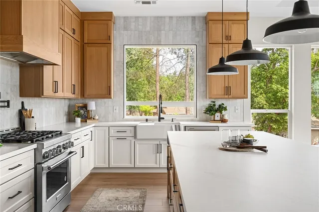 a kitchen with stainless steel appliances granite countertop a refrigerator a sink dishwasher a stove and white cabinets with wooden floor