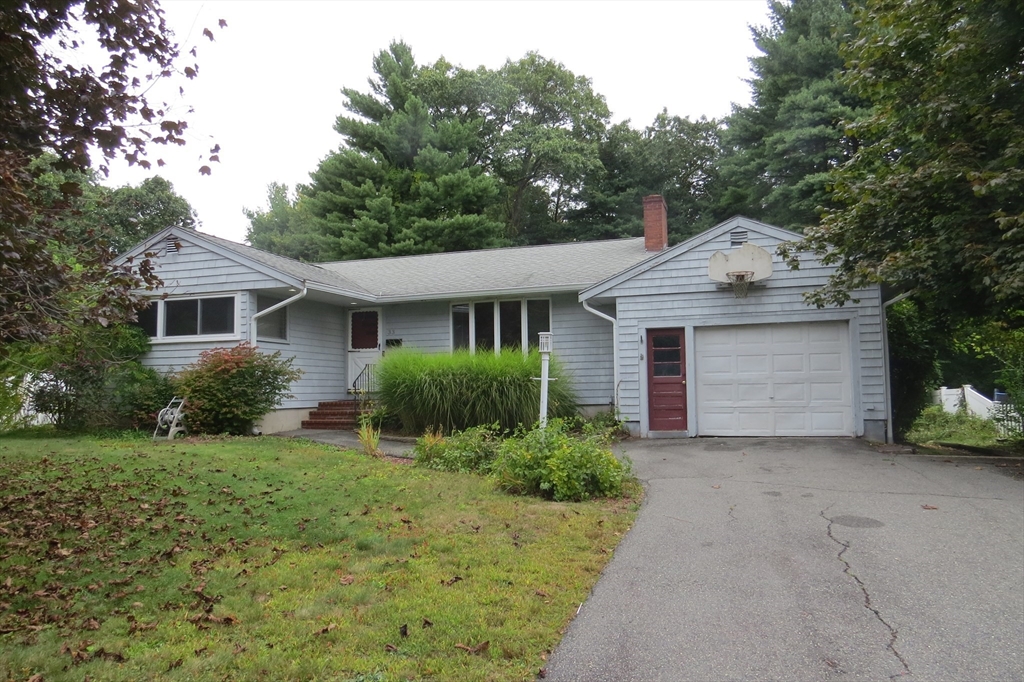 a front view of a house with a garden and trees