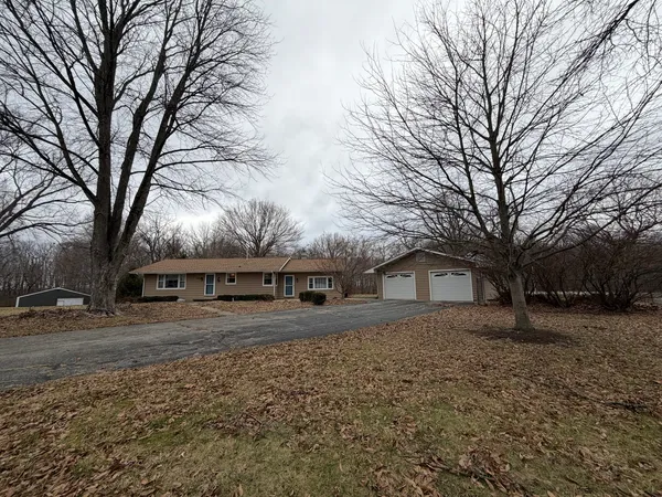 a big house with large trees and wooden fence