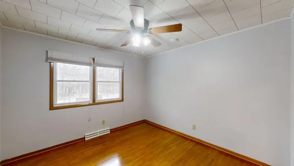 an empty room with wooden floor and fan