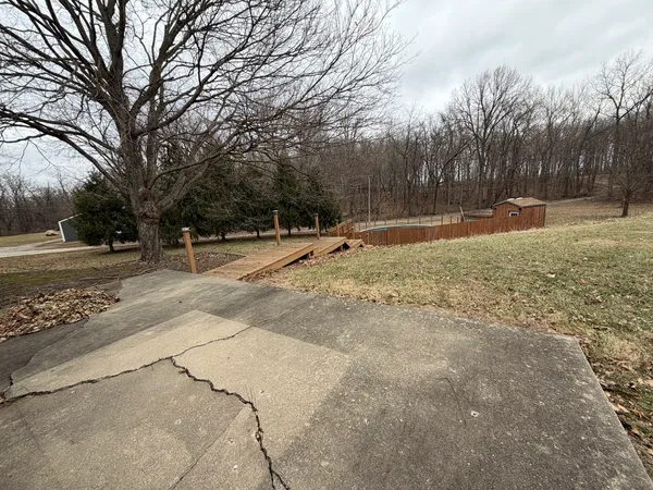 a backyard of a house with large trees and wooden fence