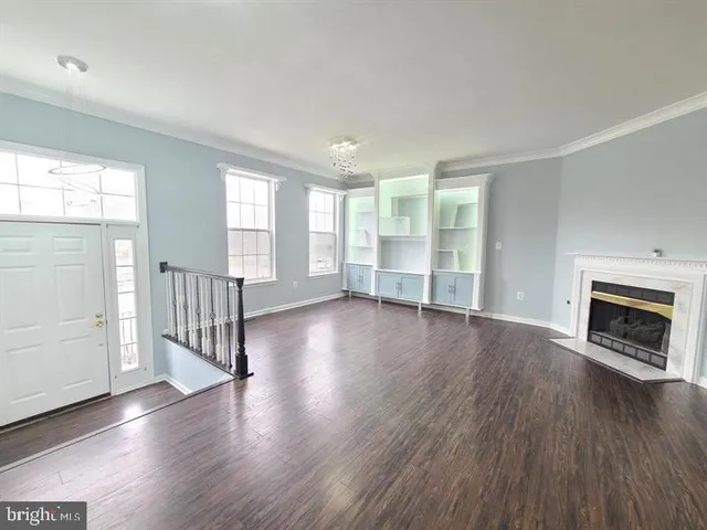 an empty room with wooden floor fireplace and windows