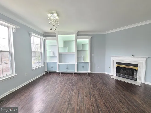 an empty room with wooden floor chandelier and windows