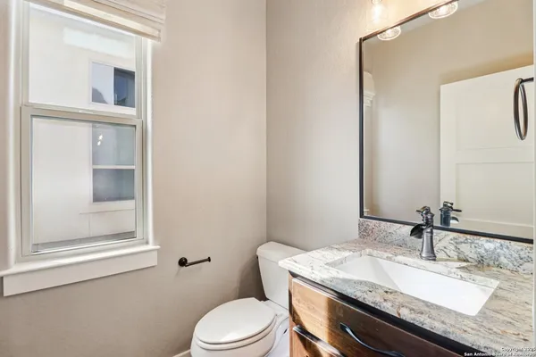 a bathroom with a granite countertop sink toilet and mirror