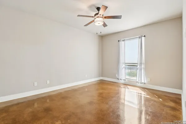 an empty room with a window and a ceiling fan