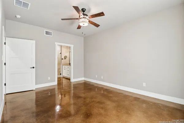 an empty room with wooden floor and ceiling fan