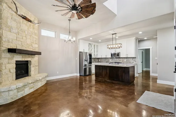 a living room with stainless steel appliances kitchen island a fireplace and a chandelier