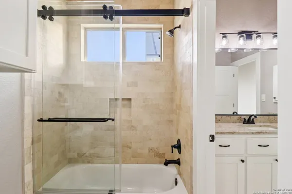 a bathroom with a granite countertop shower sink and mirror