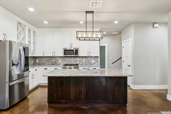 a kitchen with kitchen island granite countertop a sink refrigerator and microwave