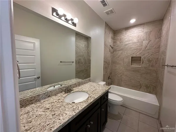 a bathroom with a granite countertop sink a toilet and shower