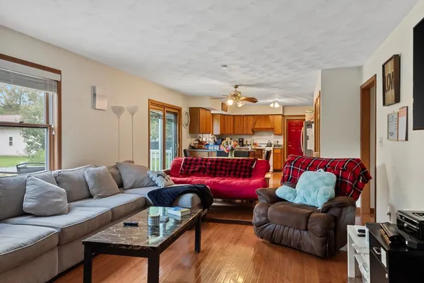 a living room with furniture a rug kitchen view and a window