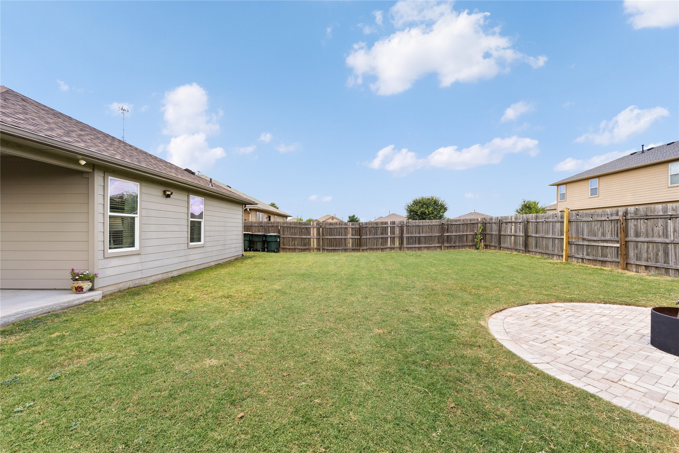 256 Alpha Kyle, TX 78640 - Photo 22 of 27 A spacious, manicured lawn offers ample outdoor living potential, bordered by privacy fencing and a paver patio.