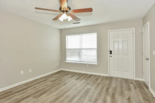 an empty room with a window and a fan