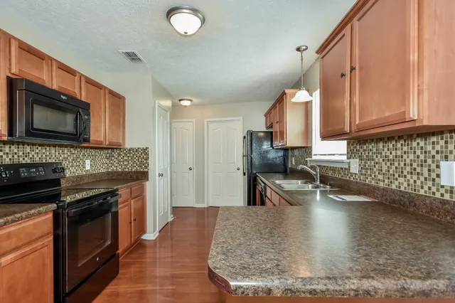 a view of a kitchen with kitchen island a sink stainless steel appliances and cabinets