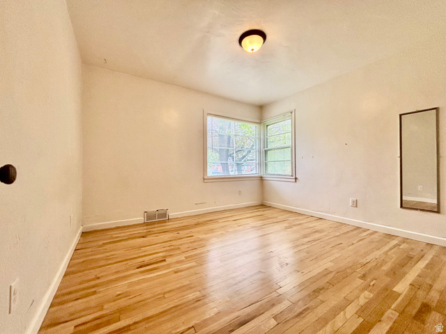 704 North 200 East Logan, UT 84321 - Photo 8 of 24 Empty room featuring light wood-style floors and a textured wall
