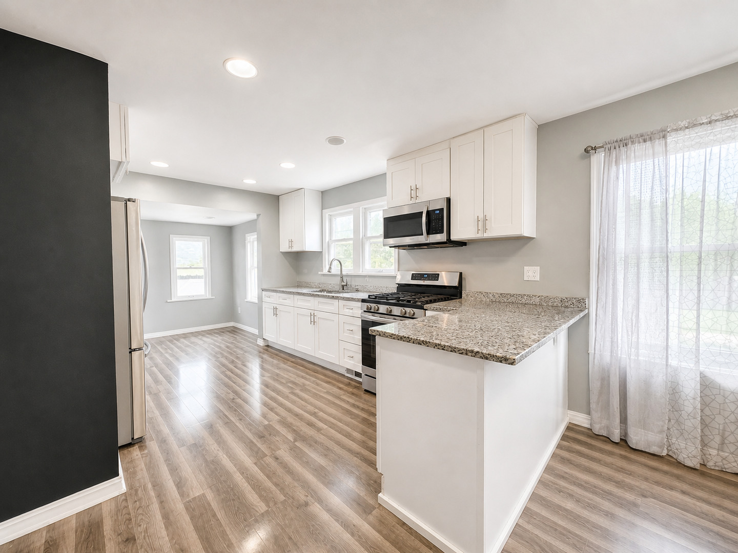 720 Adams Street Elgin, IL 60123 - Photo 5 of 16 a kitchen with stainless steel appliances granite countertop a stove a sink and white cabinets with wooden floor